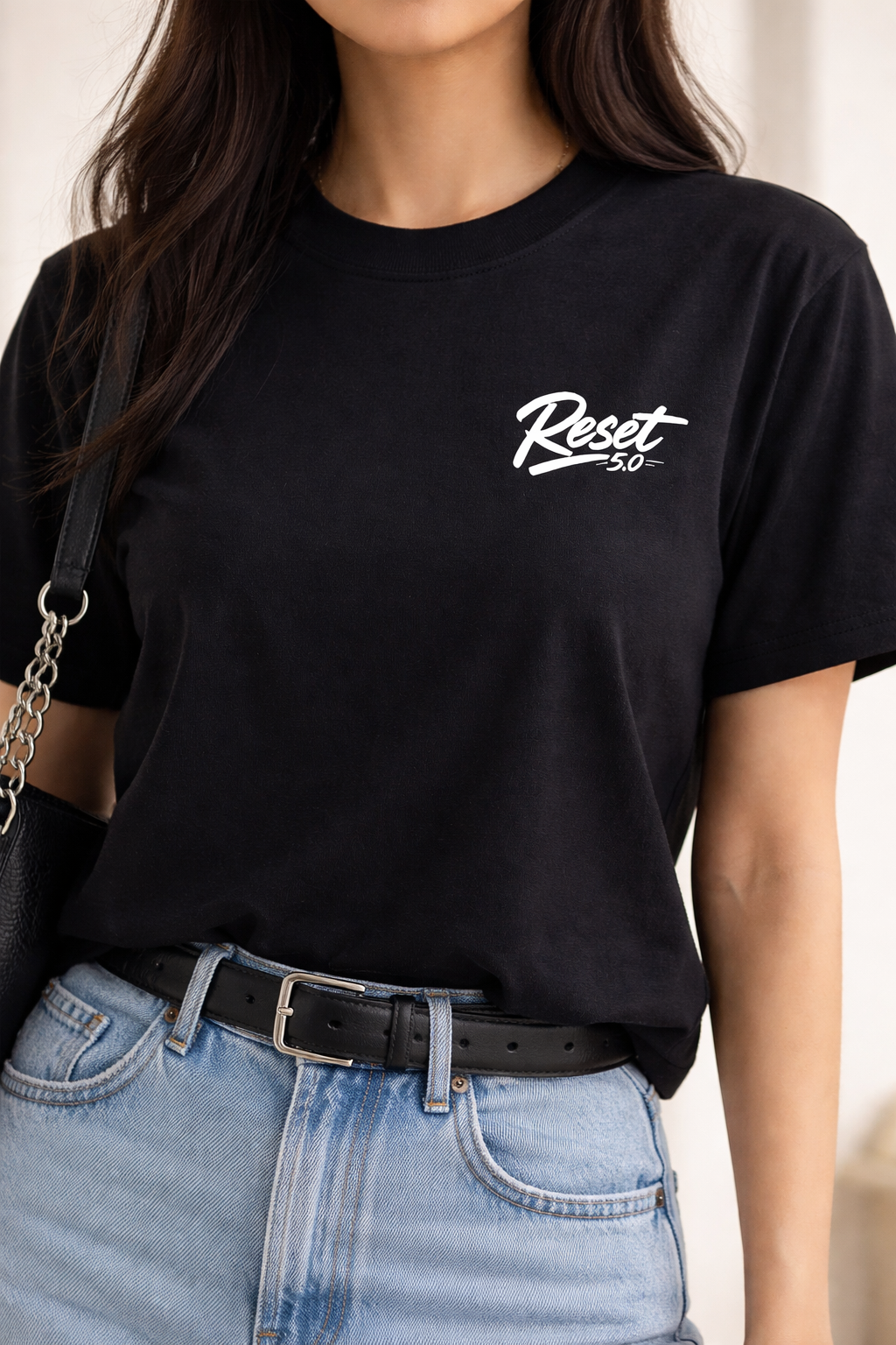 Person wearing a black t-shirt with 'Reset 50' logo, paired with blue jeans.