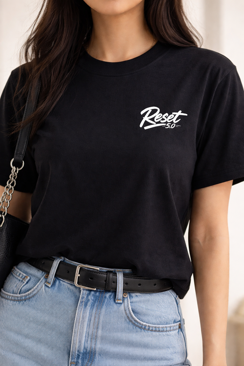 Person wearing a black t-shirt with 'Reset 50' logo, paired with blue jeans.